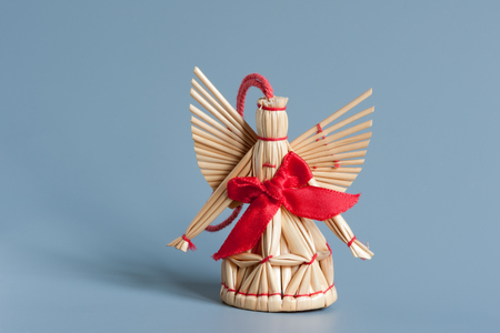 Angel figure made of straw with a red ribbonの写真素材