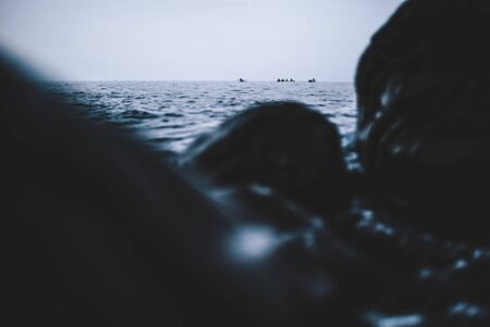 Small single boat in the distance and big rocks and water in the foregroundの写真素材