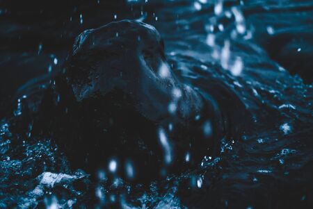Wave hitting rock with single water drops