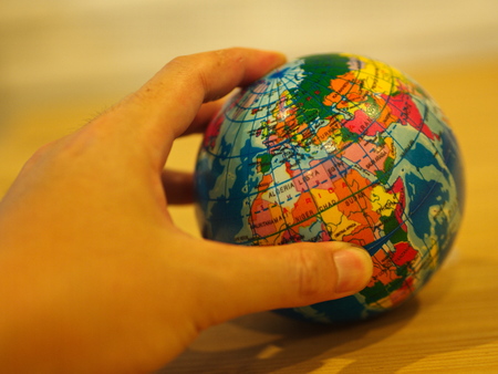 Close Up Hand holding a Mini Globe with Wooden Table Backgroundの写真素材