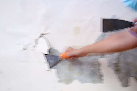 Blurry Working Concept. Removing old paint from the old wall by hand with a metal spatula. Painting Preparation at homeの写真素材