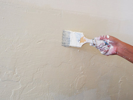 Female Hand painting the wall with paint brush. Home renovating with colorの写真素材
