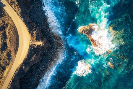 Rocky coastline and highway with golden sand and blue water, post processed in HDR