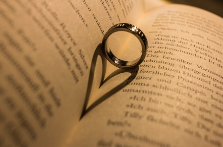 A ring casts a heart-shaped shadow in a bookの写真素材