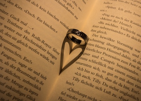 A ring casts a heart-shaped shadow in a bookの写真素材