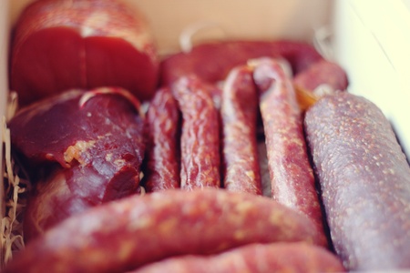 Assorted meat products including ham and sausages in a wooden box.の写真素材