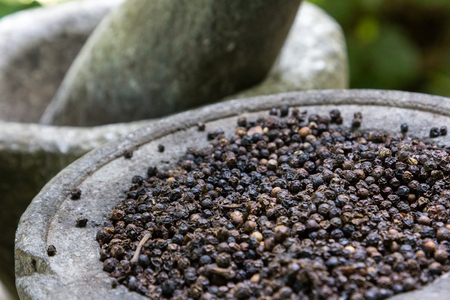 Black peppercorns in a stone vessel.の写真素材