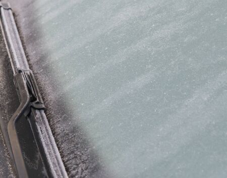 frozen windshield Close up photo and car wiper in winter. Frozen windshield of a car with ice and...