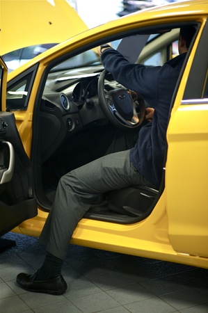 Car Salesman Showing Vehicle Interior  Small Yellow City Car  Dealership 