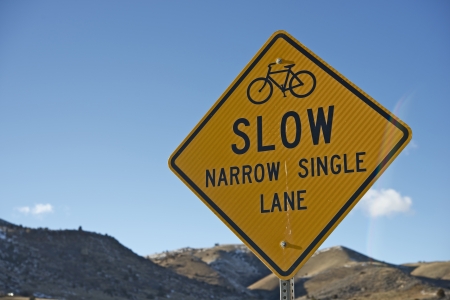 Slow Sign for Bikers. Slow - Narrow Single Lane Yellow Traffic Sign Closeup.