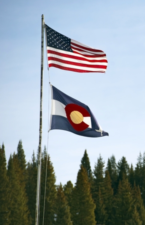 Colorado State and United States Flags Waving on High Metal Pole.