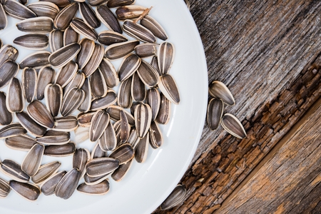 Organic Sunflower Seeds on White Plate on the Wooden Table. Sunflower Seeds Closeup.の写真素材