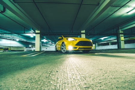 The Parking Space. Yellow Sports Car in Underground Parking at Night.