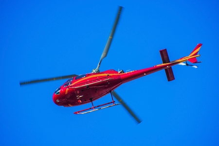 Red Tour Helicopter on the Clear Sky. Red Chopper Flying Over Head.