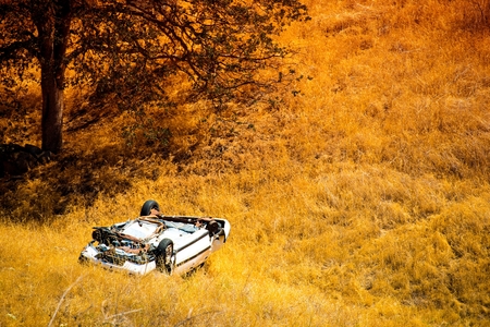 Rollover Compact Car Crash. White Crashed Car in the Mountain Road Ditch in California, USA. Traffic Accident.の写真素材