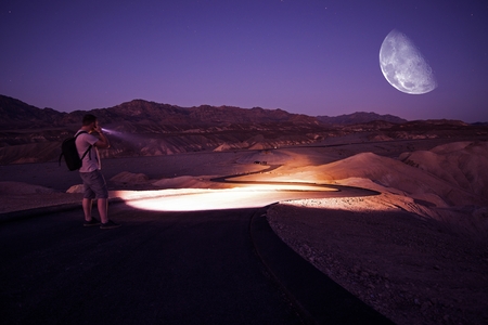 Hiker with Powerful Flashlight on Death Valley Trail During Starry Night. Night in Death Valley...