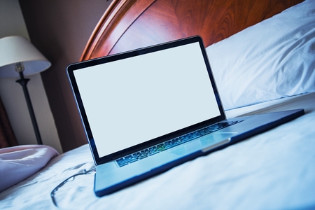 Computer in Bed Concept Photo. Browsing Internet and Working From Bed Concept.の写真素材