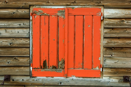 Old Orange Painted Wooden Window Covers in Rustic Wooden Cabin.の写真素材