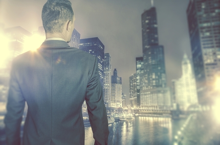 Business in the City Concept. Young Ambitious Businessman in Front of Large City with Skyscrapers.の写真素材