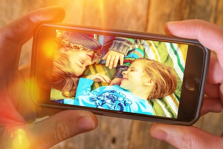 Family Vacation Memories. Photography Stored in a Cloud. Online Photography Storage Concept. Caucasian Men Browsing Last Summer Family Vacation Photos on His Smartphone.の写真素材