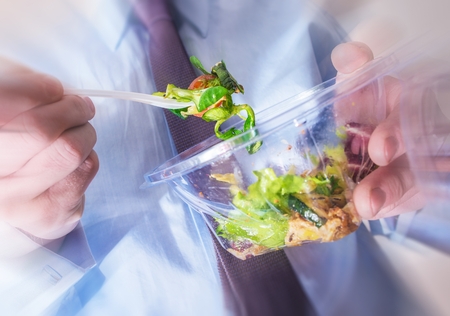 Healthy Office Food Eating Concept Photo. Office Worker Eating Diet Food. Salad From Plastic Container.の写真素材
