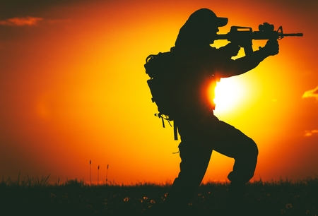 Army Trooper with Assault Rifle in Mission. Military Mission at Sunset. Military Concept.の写真素材