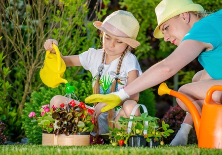 Mother and Daughter Working in Backyard Garden. Girl Learning How to Take Care of Garden Plants. Taking Care of Backyard Garden.の写真素材