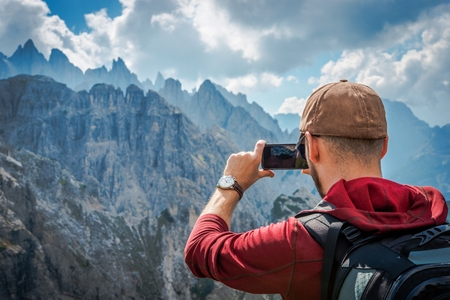 Hiking Tourist Taking Photos Using His Hi-End Smartphone Device. Travel Concept. Mountain Hiker.の写真素材