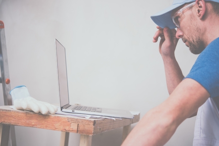 Construction Business Concept. Caucasian Worker with Laptop Computer Checking Project Schedule.の写真素材