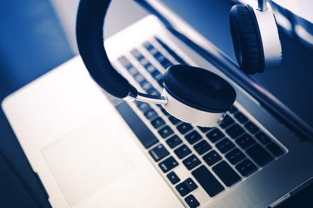 Modern Computer and Elegant Wireless Headphones on the Glassy Desk.の写真素材