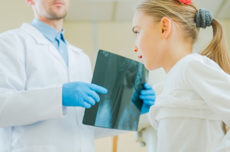 Caucasian Girl Being Examined by Professional Medical Doctor. Reviewing X Ray Imagery.の写真素材