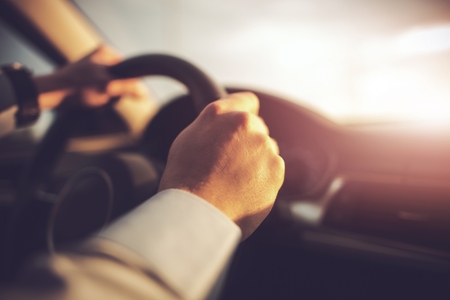 Car and the Driver Concept Photo. Hands on Steering Wheel of Modern Vehicle. Car Traveling.の写真素材