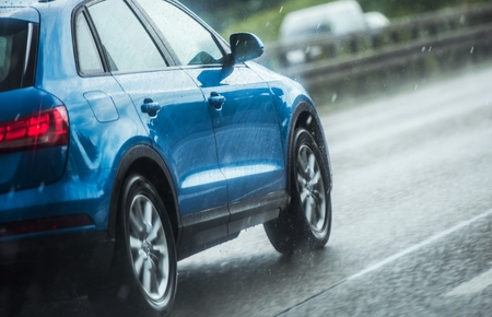 Car Driving in Heavy Rain. Blue Modern Vehicle on the Highway During Summer Storm with Heavy Rainfall.の写真素材