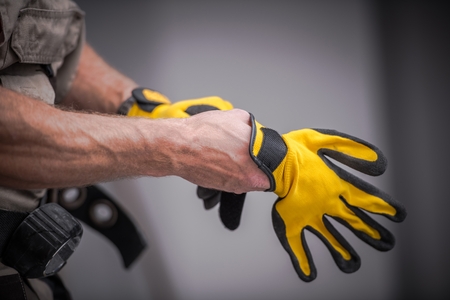 Wearing Construction Safety Gloves Closeup Photo. Caucasian Contractor Preparing For a Job.の写真素材