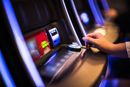 Casino Slot Machine Games Playing. Woman Hand on the Machine Bet Button. Closeup Photoの写真素材