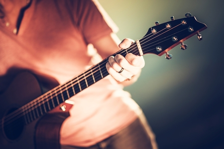 Guitar Neck Handling Closeup Photo. Musician Playing Acoustic Guitar. Shallow Depth of Field.