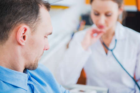Caucasian Men in His 30s Visiting Doctor Office and Awaiting Diagnosis. Caucasian Female Doctor in...