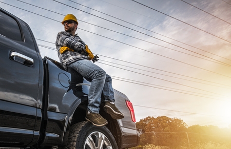 Caucasian Construction Worker Relaxing on His Pickup Truck. Freelance Handyman Workerの写真素材