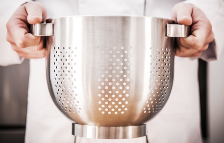 Chef with Stainless Steel Colander in Hands. Cooking and Kitchen Utensil Theme.の写真素材