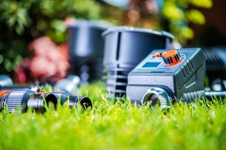 Garden Watering System Elements in the Grass. Closeup Photo. Building Automatic Backyard Water Sprayers.の写真素材