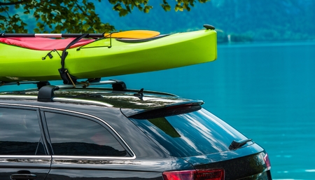 Kayak Roof Rack and the Green Kayak Mounted on the Vehicle Roof. Vacation on the Water Theme. Scenic Lake in the Background.の写真素材