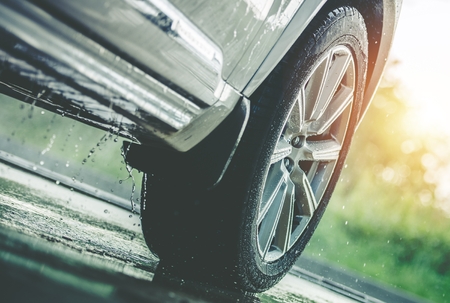 Car Driving in the Rain. Modern Rain Summer Season Tires on the Wet Pavement. Closeup Aquaplaning Photo.の写真素材