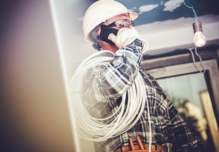 Electric Contractor Job. Professional Electrician Making Phone Conversation with Investor.の写真素材