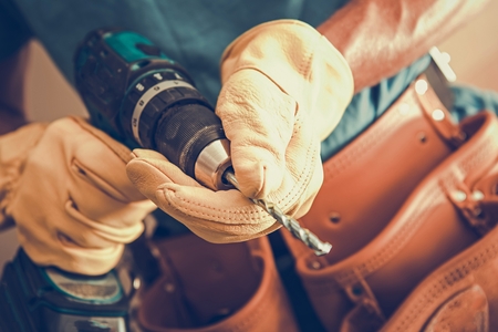 Contractor with Power Tool Closeup Photo. Cordless Driller in Hands of Caucasian Construction Worker.の写真素材