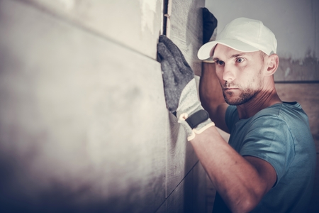 Caucasian Contractor in His 30s Installing Bathroom Walls Tiles. Accurate Installation,.の写真素材