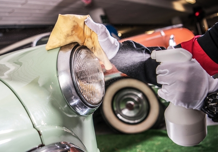 Vintage Car Cleaning and Detailing. Worker Spraying Cleaning Liquid on the Car Body.