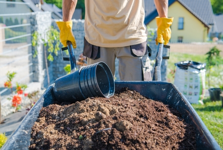 Caucasian Men Building Garden by Moving Soil in the Barrow. Gardening Theme.