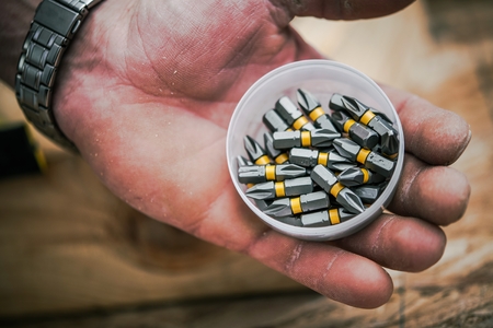 Screwdriver Bits in Hand of Construction Worker. Closeup Photo.