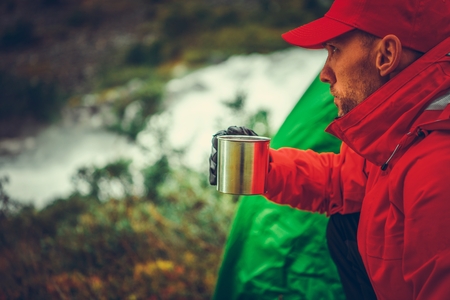 Campsite Hot Tea Time. Caucasian Outdoor Man Taking the Moment For the Relaxing Hot Drink in the Wild.の写真素材