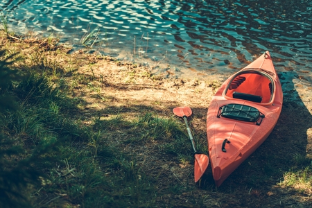 Summer Kayak Trip. Red Plastic Kayak on the Lake Shore.の写真素材